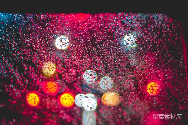 高清摄影 一幅雨后窗户的特写镜头，背景中有交通信号灯。