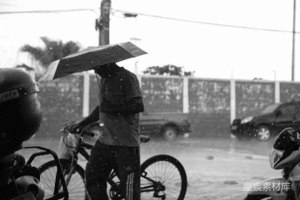 高清摄影 伞下行人骑自行车在雨中漫步。