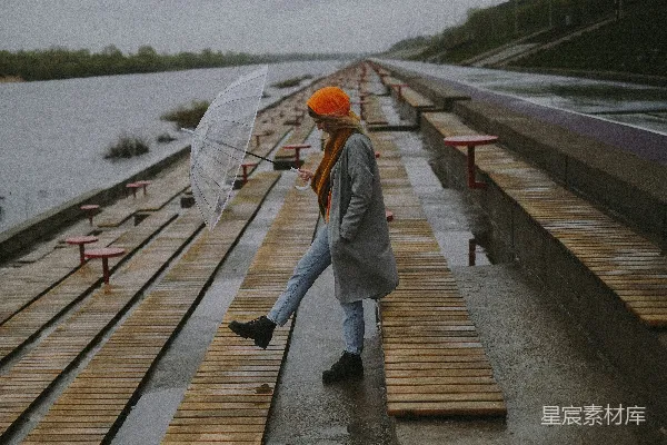 高清摄影 一个撑着雨伞的女人走在木板步行道上