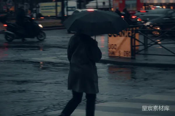 高清摄影 一位妇女正在街上行走，手中撑着雨伞。