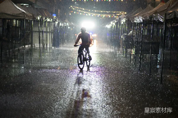 高清摄影 一个男子在一条雨水浸湿的街道上骑自行车