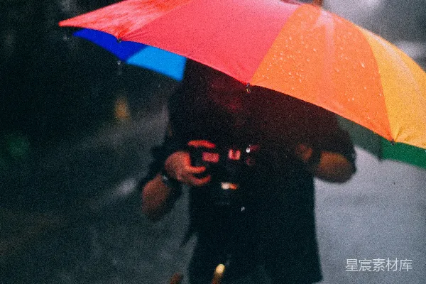 高清摄影 手持相机并打着彩色伞的男人站在雨中