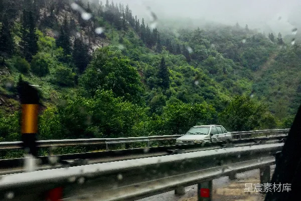 高清摄影 一辆车沿着一片郁郁葱葱的山坡上路行驶。