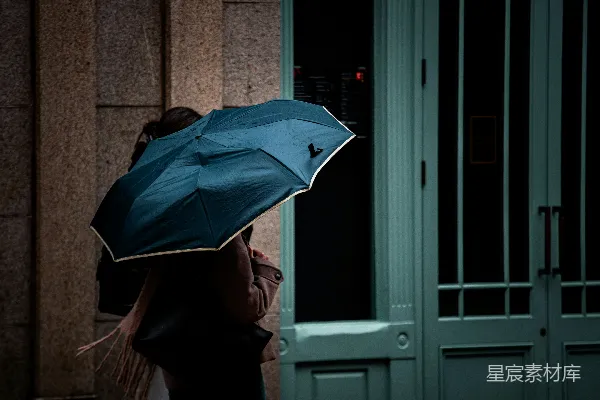 高清摄影 手持蓝色雨伞的人在雨中。