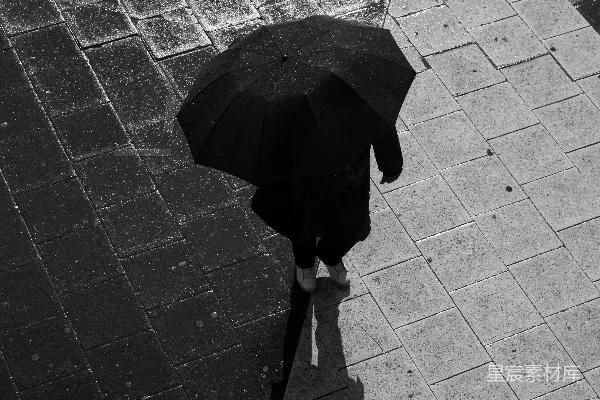 高清摄影 一个人在雨中走在人行道上，手中持着一把伞。