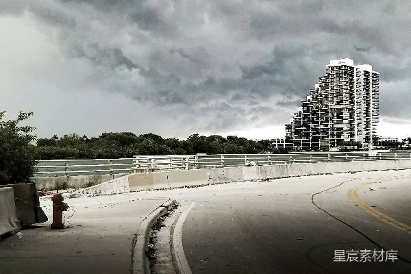 高清摄影 白天灰白色混凝土路旁有城市建筑，在白云下。