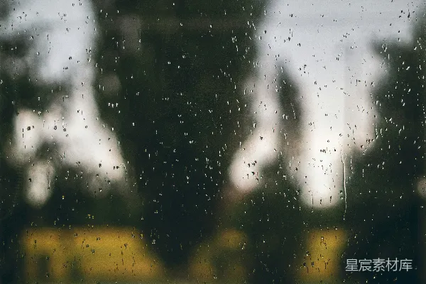 高清摄影 窗外模糊的树影下，滴滴雨珠落在玻璃上。
