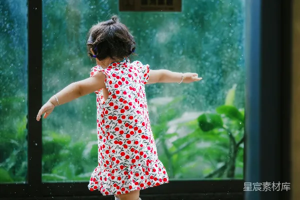 高清摄影 小女孩穿着樱桃色的连衣裙在雨中玩耍。