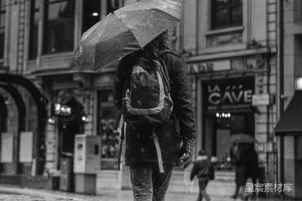 高清摄影 拿着雨伞的人在城市街道上行走着。