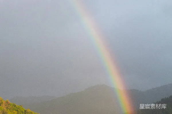 高清摄影 彩虹在雾气缭绕的山峦和绿坡上蜿蜒。