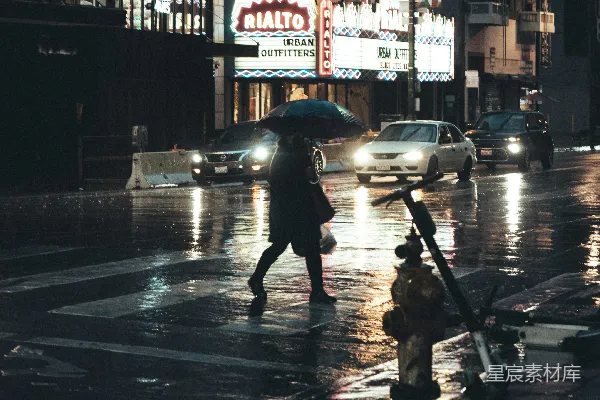 高清摄影 黑色夹克的人拿着雨伞在夜晚步行于人行道上