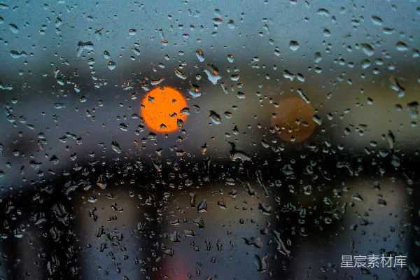 高清摄影 窗户上的雨滴与模糊的橙色灯光