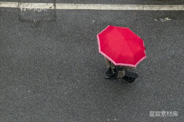 高清摄影 红色雨伞下的行人正在灰色的柏油路上白天行走。