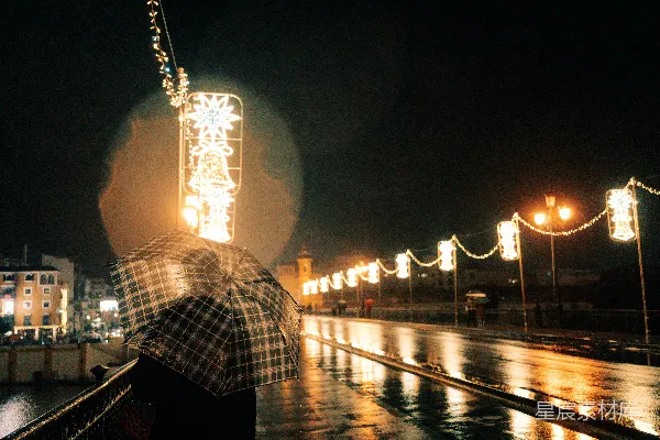 高清摄影 雨湿街道上的人带着伞，夜晚有节日灯光。
