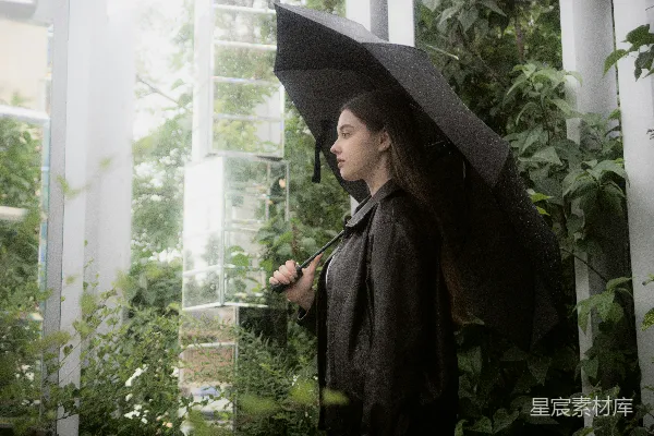 高清摄影 一个女子撑着伞，周围是绿植。