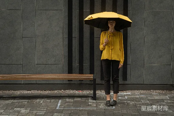 高清摄影 黄色夹克和黑色裤子的女人手持雨伞