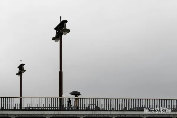 高清摄影 桥下两人撑伞，灯光照亮。