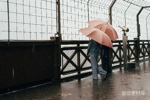 高清摄影 两个带着粉色伞的人在雨中观景台观察。
