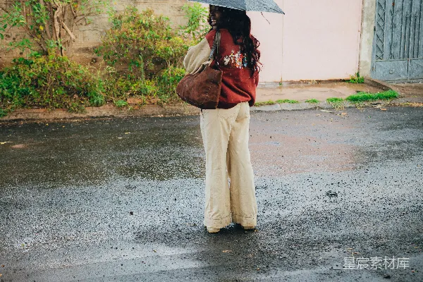 高清摄影 带着伞的女人站在湿漉漉的街道上
