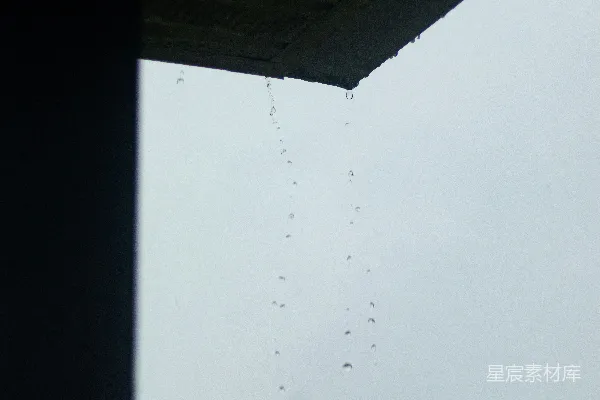 高清摄影 屋顶檐口处的雨滴在灰色的天空下落下。
