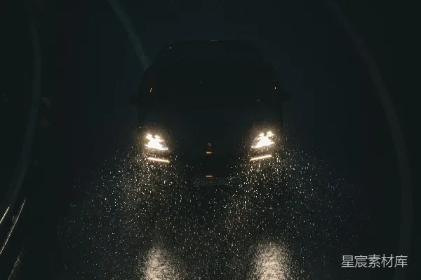 高清摄影 汽车大灯在夜间照亮一条湿滑的道路。