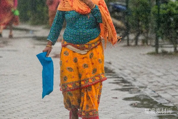 高清摄影 妇女在雨中行走，手持一块蓝色的布。