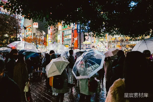 高清摄影 夜晚，人们打着伞走在雨中的城市里。