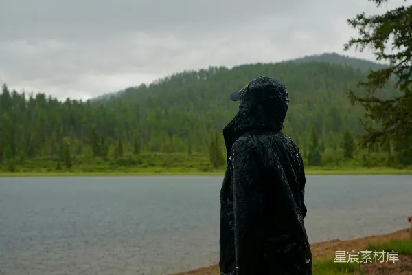 高清摄影 穿着雨衣的人望着湖上的雨。