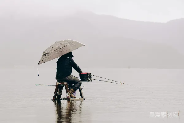 高清摄影 人在雾天撑伞钓鱼的场景。