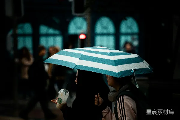 高清摄影 人们在一条纹的伞下夜行。