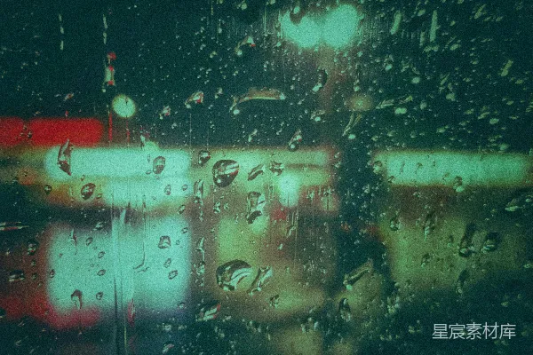 高清摄影 夜幕下的窗玻璃上挂着几滴雨水，映照着模糊的城市灯光。