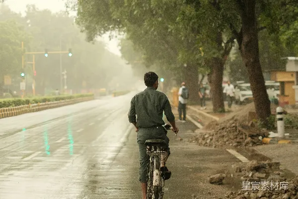 高清摄影 一个男子在一条雨水淋湿的街道上骑自行车。