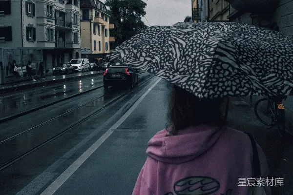 高清摄影 女人在雨中撑伞走在城市街道上。