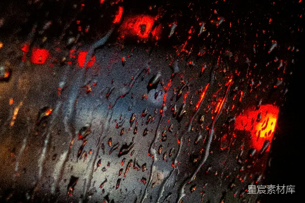 高清摄影 窗外模糊的红灯下，雨滴落在玻璃上。