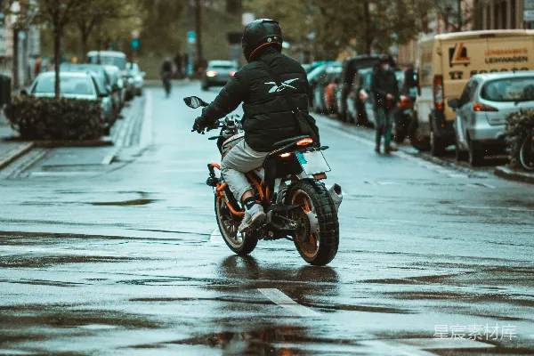 高清摄影 一个男人在一条被雨水浸湿的街道上骑着摩托车。