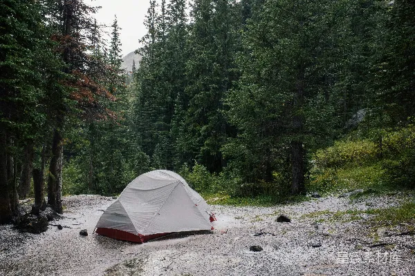 高清摄影 湖边有一座灰色的小屋，周围被树木环绕。