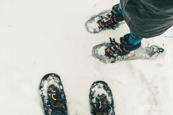高清摄影 黑色裤子和黑白雪地靴的人站在覆盖着积雪的地面上