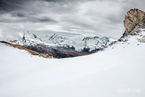 高清摄影 棕色山被覆盖在黑暗的云层笼罩的天空下白雪皑皑。