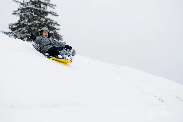 高清摄影 黑色夹克的人在雪地上白天骑着黄色的雪撬滑行