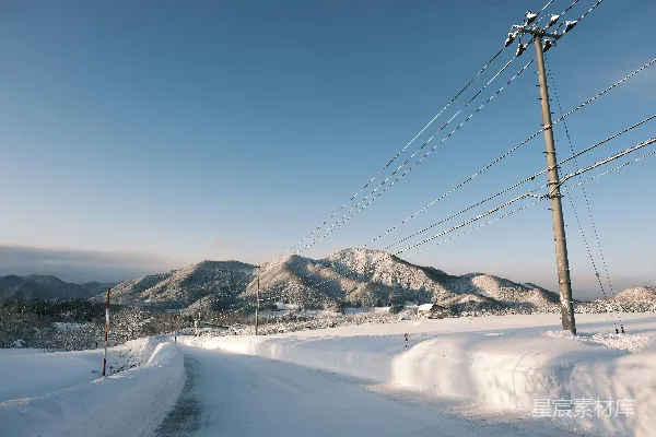 高清摄影 覆盖着白雪的道路，背景是电线和山脉。