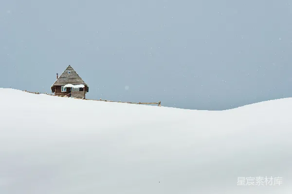 高清摄影 一座小屋坐落在白雪覆盖的山坡上。