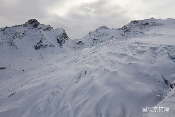 高清摄影 远处一座被雪覆盖的山峦和一条缆车轨道在其中显现。