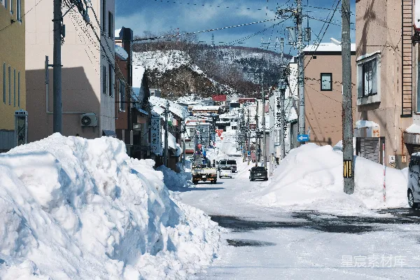 高清摄影 城市街道上覆盖着白雪，背景是连绵的山峦。