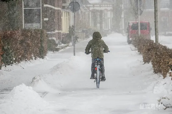 高清摄影 棕色风衣女子在覆有白雪的道路骑自行车的白天场景