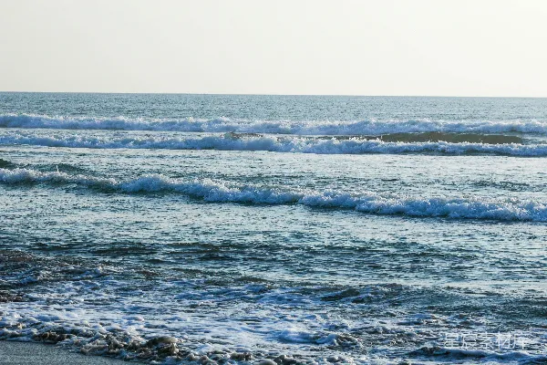 高清摄影 一个骑着冲浪板的人漂浮在波涛汹涌的海滩上