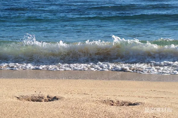 高清摄影 沙滩上波浪拍打着的海滩与脚印交织。