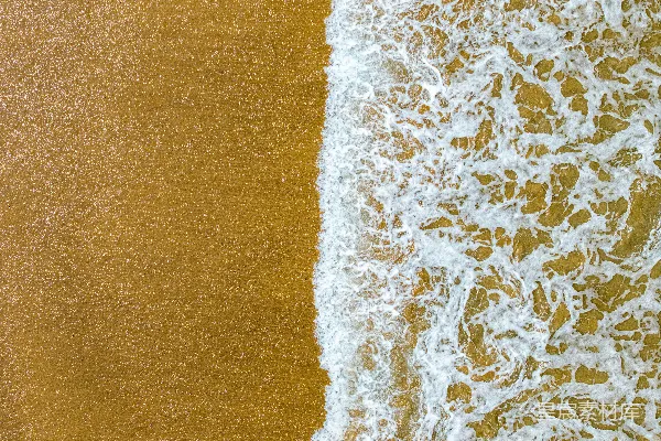 高清摄影 波涛汹涌的金色沙滩上泛起泡沫的海浪。
