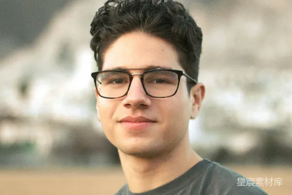 高清摄影 一个戴眼镜的年轻人站在山前。