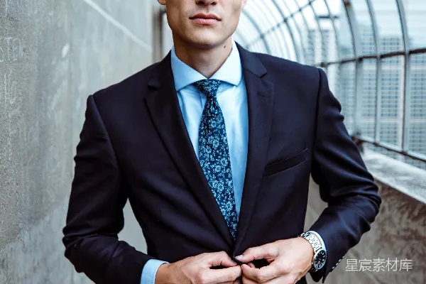 高清摄影 身穿黑色和 teal 深蓝色西装的男士站在灰色墙壁附近