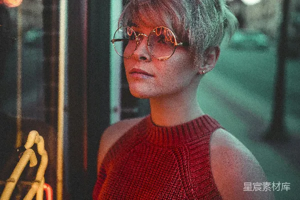 高清摄影 戴眼镜的女人正在看着一块玻璃面板上的霓虹招牌。